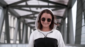 Beautiful brunette girl walks around the city. Woman in a hood posing for the camera. Slow motion