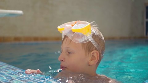 cute boy in a scuba diving mask is swimming in pool. Summer holidays. Rest at the hotel. School holidays. A child on the background of beautiful clear water in a swimming pool. Rest, fun, pleasure