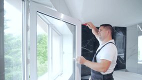 worker installs and adjusts a new plastic window in house. repair regulates Installation and adjustment Workman in overalls installing or adjusting plastic windows in room at home. maintenance service