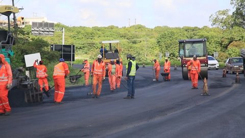 camacari, bahia, brazil - august 24, 2021: workers are seen doing asphalt recap of the access lane to the industrial hub of the city of Camacari.