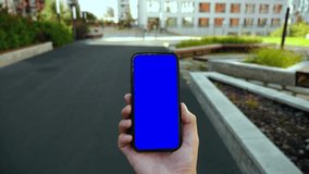 Man Walking and Use Smartphone Green Screen Chroma Key Point of View. Caucasian Person Hold in Hand Phone Mock-up and Watching Video Show, Surfing Browsing Internet. Go in Urban Phone Mobile Close-up