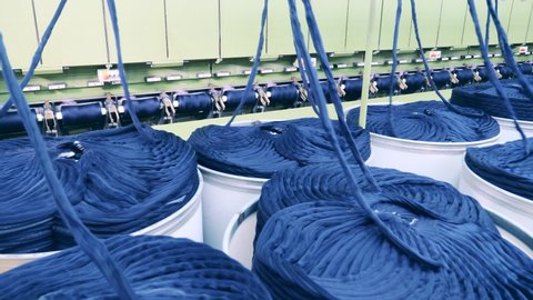 Machinery complex is unreeling coils of blue yarn