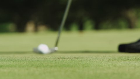 Close up of a guy making a put at the golf course.