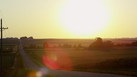 Static view of fields with the sun above the horizon, with sun flares.