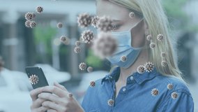 Animation of covid 19 virus cells over woman wearing face mask using smartphone. global covid 19 pandemic concept digitally generated video.