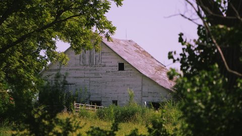 Static view of old white barn through the trees in Auburn, Nebraska.