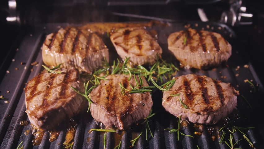 Delicious juicy meat steak cooking on grill. Prime beef fry on electric roaster, rosemary, black pepper, salt. Slow motion. | Shutterstock HD Video #1078156436