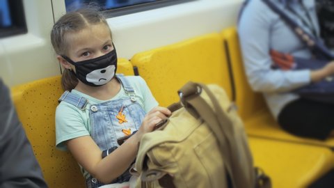 Little girl travel caucasian ride at overground train airtrain with wearing protective medical red mask. Child baby at airtrain. People in mask.