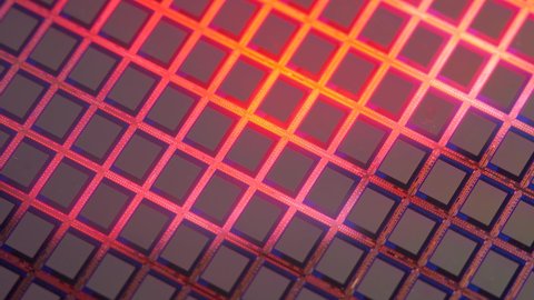 Silicon wafers reflect red light. Modern electronics, semiconductor of electricity. Formed silicon into semi-conductive wafers for integrated circuits or microchips, computer chips