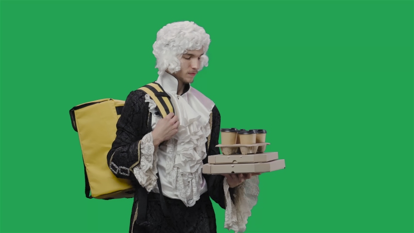 Portrait of courtier gentleman in black historical vintage suit and white wig, delivering food and drinks. Young man posing in studio with green screen background. Close up. Slow motion ready 59.94fps