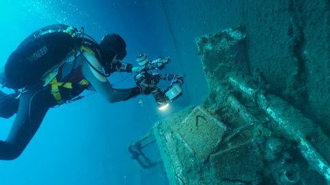 MEDITERRANEAN SEA, CYPRUS - AUGUST, 2021: Scuba diver photographer shots cabin truck on the shipwreck Swedish ferry MS Zenobia. Slow motion, Wreck diving. Mediterranean sea, Cyprus