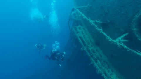 MEDITERRANEAN SEA, CYPRUS - AUGUST, 2021: Group of scuba divers swims above shipwreck Swedish ferry MS Zenobia. Slow motion, Wreck diving. Mediterranean sea, Cyprus