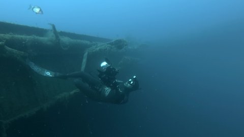 MEDITERRANEAN SEA, CYPRUS - AUGUST, 2021: Free diver photographer swims on the shipwreck Swedish ferry MS Zenobia. Wreck diving. Mediterranean sea, Cyprus