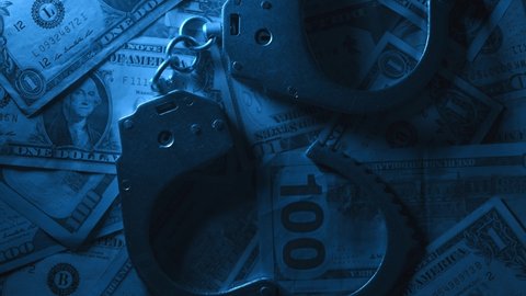 Close up of rotation metal handcuffs over stack of dollar banknotes. Dirty money. Concept of financial crimes or bribery and cash corruption police and deputies or fraud. 4k footage