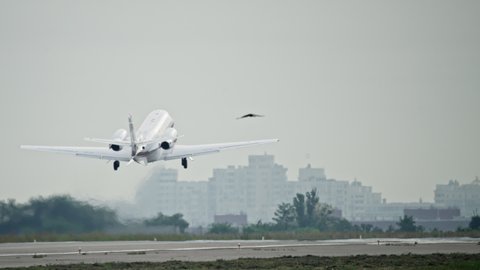 A small private plane takes off in urban scenery. The wheels of a light aircraft detach from the runway of the airport.