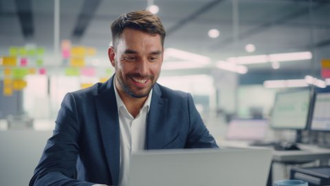 Busy Young Businessman Using Laptop Computer in Modern Office. Manager Thinks About Successful Financial Ideas. Happy Man Smiling About Finding Problem Solving Solutions for Company.