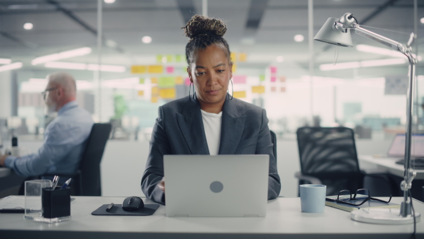 Portrait of a Happy African American Businesswoman Using Laptop Computer in Modern Office. Stylish Beautiful Manager Smiling, Working on Financial and Marketing Projects. Camera Zoom In. Royalty-Free Stock Footage #1078185098