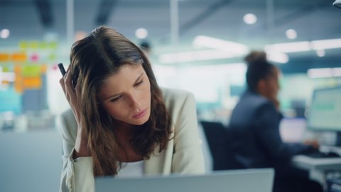 Young Serious Female Manager Using Computer in Modern Office. Overworked Tired Employee Dealing with Hard Work Tasks. Stressed Beautiful Woman Exhausted to Come Up with New Business Ideas.