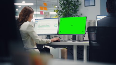 Young Confident Businesswoman Using Desktop Computer with Green Screen Mock Up Display in Modern Office. Manager Working on Commercial, Financial and Marketing Projects. Specialist in Diverse Team.