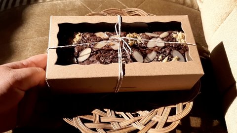 A gift box filled with almond-topped brownies. Brownies are baked or steamed foods that are square, flat and bar.