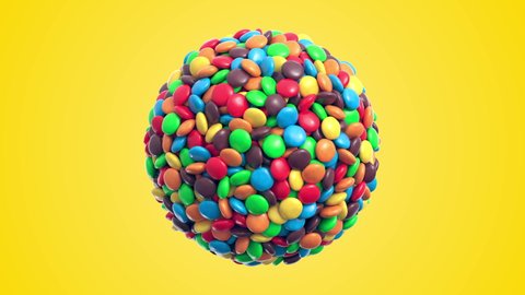 Colorful coated chocolate candies in the shape of a sphere rotate on yellow background. Seamless loop. Alpha layer is included. 3d rendering