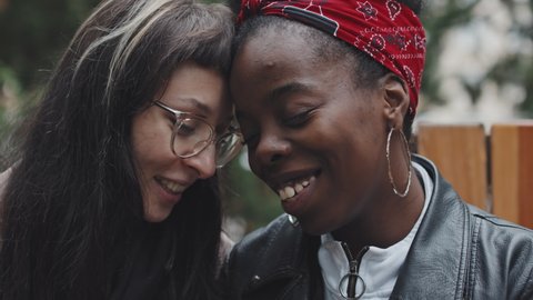 Close up slowmo of affectionate Caucasian woman and African-American woman laughing and being affectionate with each other outside Video Stok