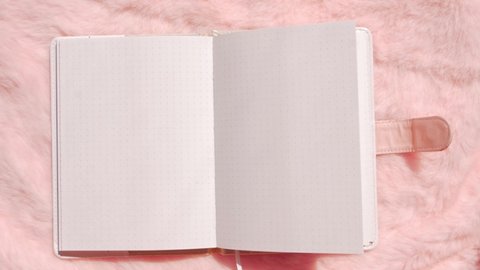 Blank notebook mockup on pink faux fur flat lay. Coral fluffy feminine fabric background top view. Female blog rose textile surface notepad copy space text sign design. White sketchbook sheet template