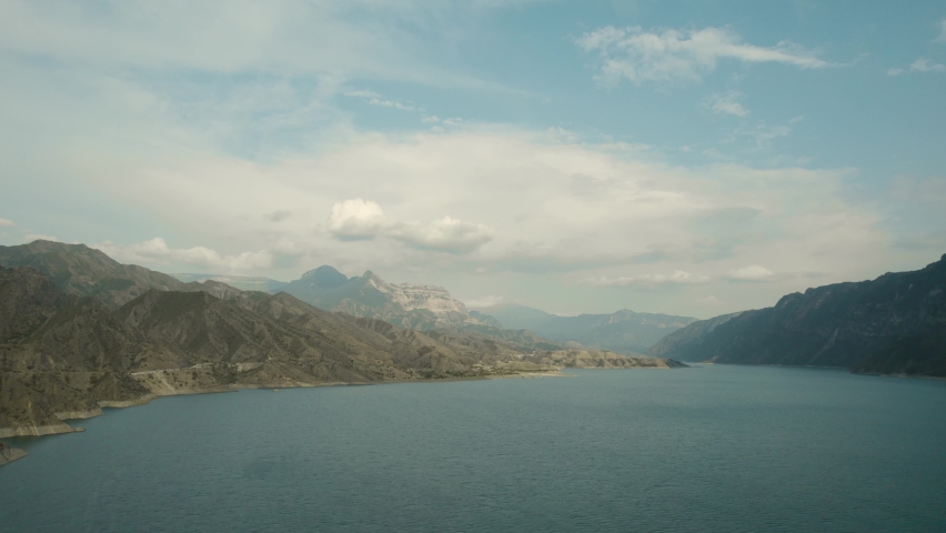 Top view of large lake in Rocky Mountains. Action. Beautiful blue lake on background of mountain horizon. Big blue lake surrounded by mountains