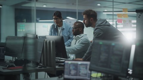 Diverse Group of Professionals Meeting in Modern Office: IT Programmers Use Computer, Talk Strategy, Discuss Planning. Software Engineers Develop Inspirational App. Rack Focus Computers to People