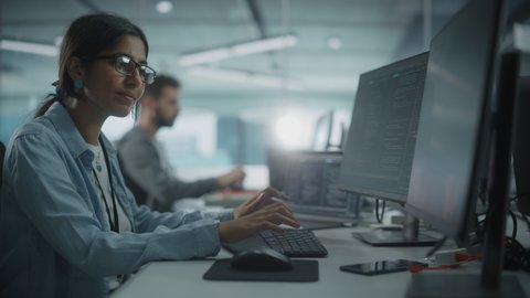 Real Diverse Office: Indian IT Programmer Working on Desktop Computer. Female Specialist Creating Innovative Software. Engineer Developing App, Program, Video Game. Writing Code in Terminal. Arc Shot