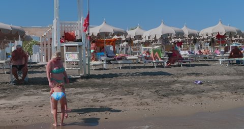 Margherita di Savoia, Italy - August 15, 2021: view from the sea of bathers on the shoreline of a lido with umbrellas, deck chairs, sunbeds, etc.