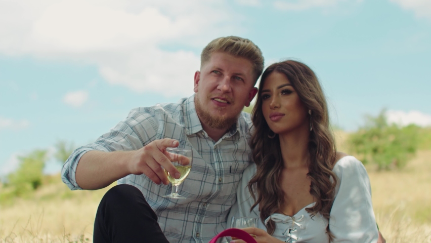 Handsome couple in love enjoying a picnic outdoors and a glass of wine. watching nature together