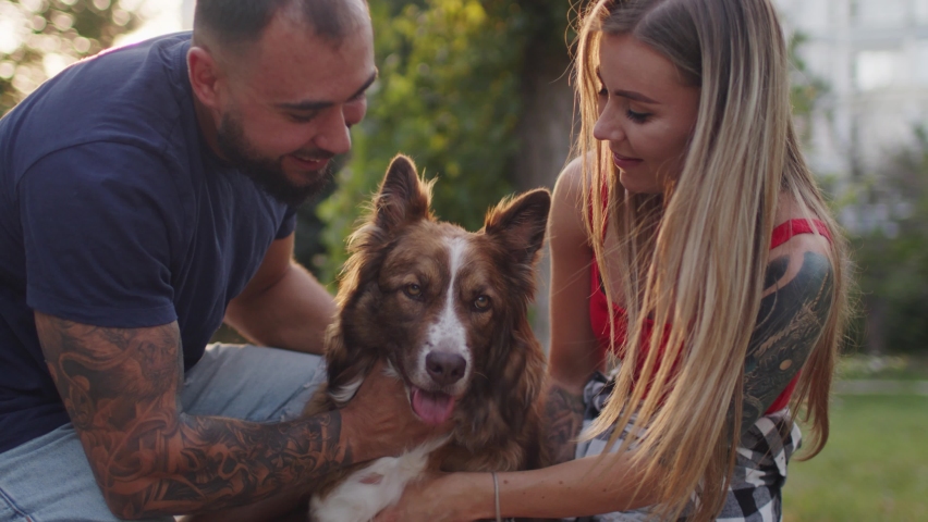 Close up of young couple petting their dog while having a walk in park | Shutterstock HD Video #1078237886