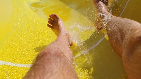 enjoying on waterslide during summer vacation, feet of man slides down the pool in water park on holiday resort