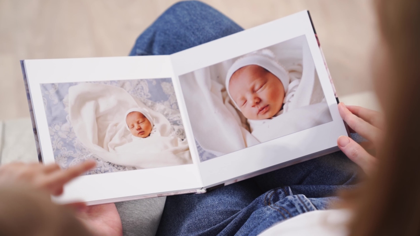 Top view. mother and daughter watch photobook from discharge of newborn baby.family tradition of printing photos and looking at them with children and remembering.photographer and designer | Shutterstock HD Video #1078239245