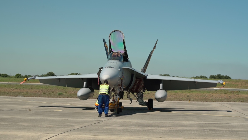 A group of mechanical engineers service check the condition of the chassis of a military fighter after flights.