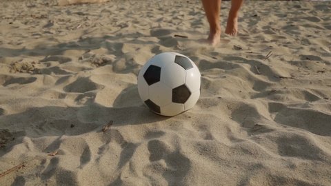 Beach soccer. A man hits a classic black-and-white leather ball. Rest outside. Summer sports. An active lifestyle. Sports activities for children and teenagers. Hobbies for men and women.