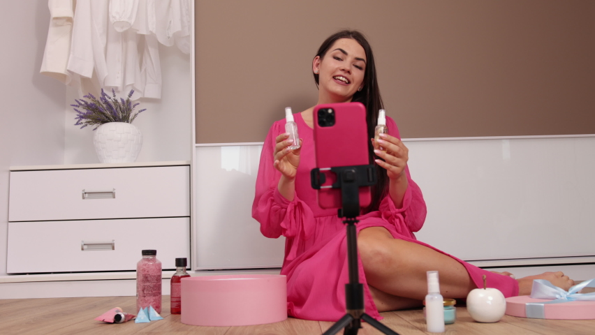 Recording video for beauty blog on camera at home, female influencer shooting brand advertising promo, beautiful young female blogger, stylist sitting in front of smartphone web camera on stabilizer
