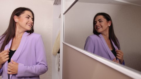 Pretty brunette woman in trendy black bra, jacket leans hanger in dressing room. Young woman choosing clothes to wear, standing wardrobe at home, a lady chooses a blouse closet in the apartment