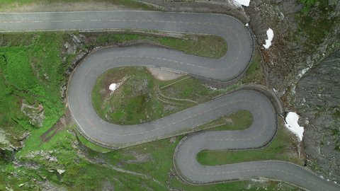 AERIAL, TOP DOWN: Drone point of view of an empty switchback road in scenic Gotthardpass, Switzerland. Flying above a hairpin road meandering across the beautiful Swiss mountains. Empty hairpin route.