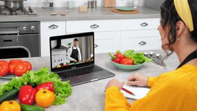 Woman in home kitchen study online video call webcam laptop tells chef teacher. Man food blogger in computer screen slices cucumber listen teaches housewife student remote culinary cooking lesson