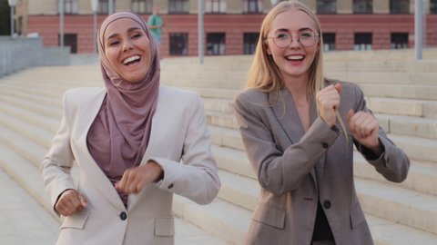 Victory dance concept, excited diverse coworkers celebrating business success, unbelievable achievement triumph, happy euphoric team female colleagues jumping dancing outdoors enjoying great win Adlı Stok Video