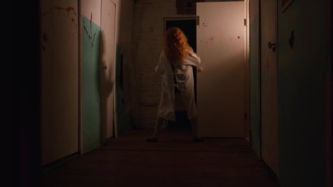 Horror acting - a woman in a straitjacket going crazy in bloody corridor of mental hospital