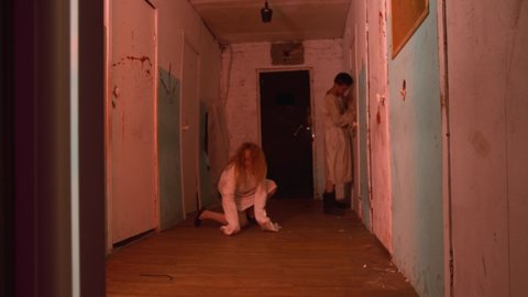 Horror acting - man and woman in the corridors of scary bloody mental hospital