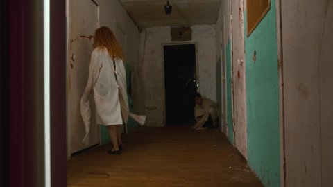 Man and woman going crazy in the corridors of scary bloody mental hospital