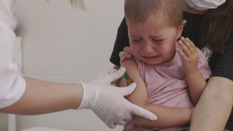 Doctor makes vaccination in the children's hands. Two years old kid crying while he is given an injection of a syringe in the shoulder close-up. 4k