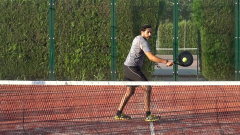Slow motion of a paddle tennis player who is practicing in an outdoor school or club.