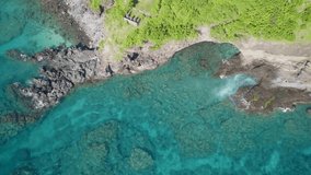 Dramatic top down aerial drone video of the coast of Nusa Lembongan with many luxury villa and hotels in Bali, Indonesia, in early morning by an idyllic beach