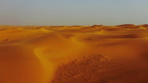 Arabian Peninsula. Flying over curve shaped gold sand dunes during hot summer weather. Aerial shot, 4K