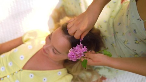 4k hd CU of young woman inserting a flowers into friends hair. 